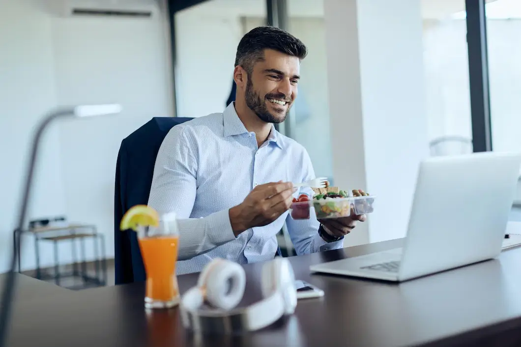 hombre-negocios-feliz-usando-computadora-portatil-mientras-almuerza-oficina_637285-8682